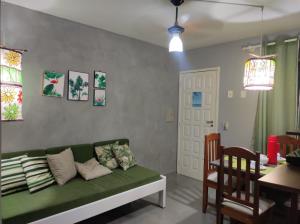 sala de estar con sofá verde y mesa en PRAIA DE TAPERAPUAN - FLAT EM CONDOMINIO A 300 METROS DA PRAIA., en Porto Seguro