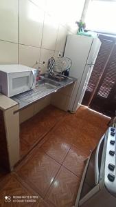 eine kleine Küche mit einer Spüle und einer Mikrowelle in der Unterkunft A casa amarela in Cabo Frio
