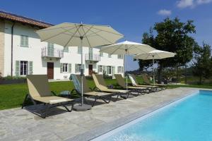 - une rangée de chaises et de parasols à côté de la piscine dans l'établissement Casa Faretto, à Costigliole dʼAsti