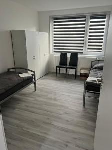 1 dormitorio con 2 camas, 2 sillas y ventana en AlWi Appartements, en Moringen