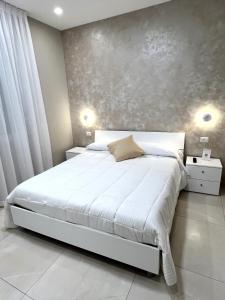 1 dormitorio con cama blanca y pared gris en B&B VIRGILIO LAMEZIA AIRPORT en SantʼEufemia Lamezia