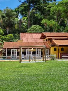 uma casa amarela com um telhado vermelho e um quintal em VILLA MIA DUO em Itaipava