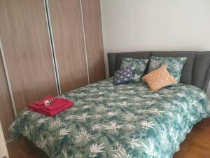een bed met een groen en wit dekbed met een handtas erop bij Appartement in Villejuif (M 7) with free parking in Villejuif