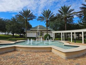 a fountain in front of a house with palm trees at Endearing Private Bedroom in Shared House in Reunion Resort in Kissimmee