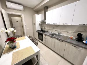 una cucina con armadi bianchi, tavolo e lavandino di B&B VIRGILIO LAMEZIA AIRPORT a SantʼEufemia Lamezia