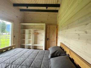 Dormitorio en cabaña de madera con cama y ventana en Cabaña Azul en Riñinahue