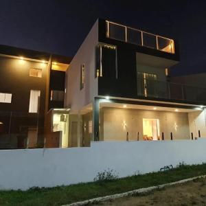 een groot huis 's nachts met een witte muur bij CASA NA BARRA DE SANTO ANTONIO in Barra de Santo Antônio