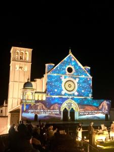 Un edificio coperto di luci natalizie di fronte a un edificio di Appartamenti Santa Chiara ad Assisi