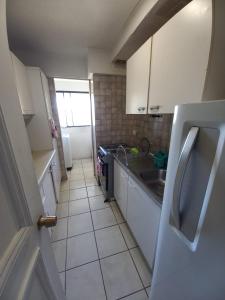 a small kitchen with white cabinets and a sink at Excelente ubicación in Concón