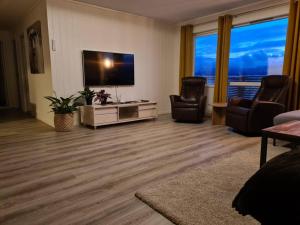 Tromsø stunning Luxury apart B في ترومسو: غرفة معيشة مع كرسيين وتلفزيون بشاشة مسطحة
