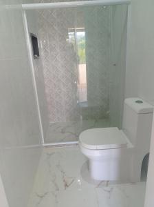 a white bathroom with a toilet and a shower at Hostel BSJ in Casimiro de Abreu