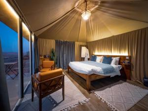 a bedroom in a tent with a bed and a chair at Milky way Domes Desert Camp in Bidiyah