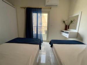 two beds in a room with a window at Entire apartment$Gorgeous hideout& CoZzy in Hurghada
