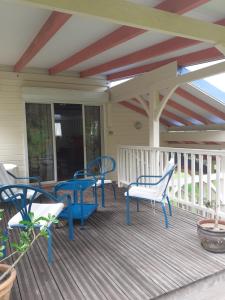 a deck with blue tables and chairs on a porch at La petite maison dans la prairie in Gros-Morne