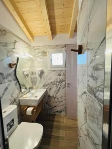 a bathroom with a white toilet and a sink at Kalyva Country House, with private beach and pool in Benitses