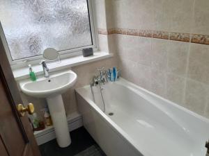uma casa de banho com um lavatório e uma banheira ao lado de um lavatório em Amazing 3 bedroom house with parking. em Nottingham