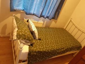 uma cama com lençóis e almofadas verdes num quarto em Amazing 3 bedroom house with parking. em Nottingham