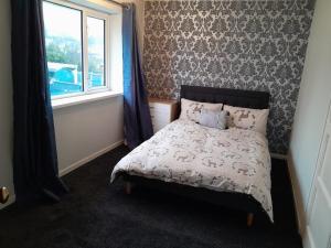 a small bedroom with a bed with a window at Amazing 3 bedroom house with parking. in Nottingham