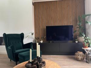 a living room with a green chair and a television at Tip Top vakantie Woning Vlissingen in Vlissingen