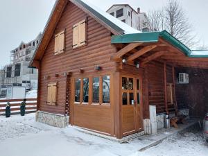een houten hut met een deur in de sneeuw bij Zara Chalet in Kolašin