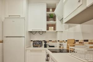 a white kitchen with white cabinets and a refrigerator at Little Arboli Little Apartments in Cádiz