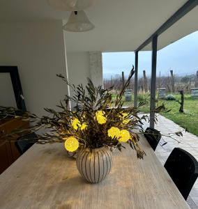 un vase avec des fleurs jaunes sur une table en bois dans l'établissement Kraska nisa, à Komen