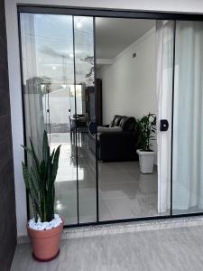 ein Wohnzimmer mit Glastüren und einer Topfpflanze in der Unterkunft Brisas de São Chico - 450m da Praia in São Francisco do Sul