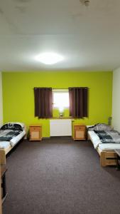 two beds in a room with green walls and a window at Penzion Bernardo in Senička