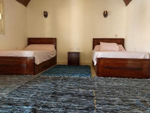 two beds in a room with two rugs at انتيكا كامب in Taba