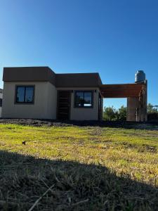 una casa con un campo de hierba delante de ella en Casa a estrenar 450 metros de la playa en Quequén
