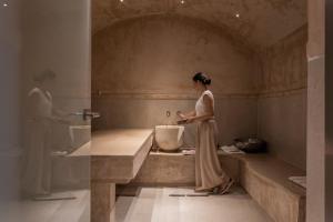 Porto Delfino Retreat في كابساليون: امرأة جالسة في حوض الاستحمام في الحمام