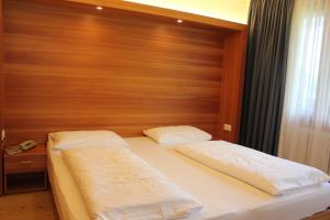 2 Betten in einem Schlafzimmer mit einem Kopfteil aus Holz in der Unterkunft Residence La Villa in Stern