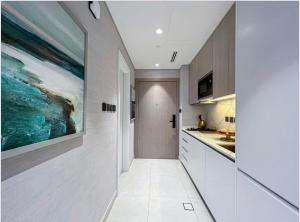 een keuken met witte kasten en een schilderij aan de muur bij Luxury New Studio with Pool & Gym Access, 5 min from Gardens Metro in Dubai