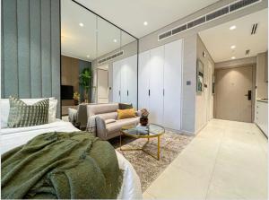 een slaapkamer met een bed, een bank en een tafel bij Luxury New Studio with Pool & Gym Access, 5 min from Gardens Metro in Dubai