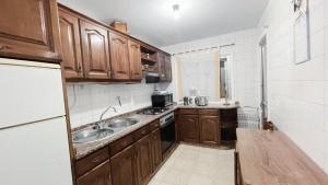 una pequeña cocina con armarios de madera y fregadero en Apartamento Familiar en Verín España, en Verín