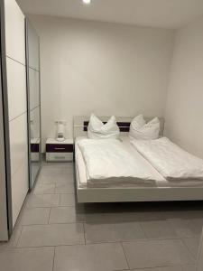 a bedroom with a bed with white sheets and a mirror at Apisha Appartement in Kirchheim unter Teck