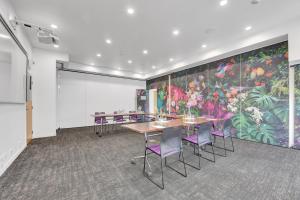 una sala de conferencias con mesas y sillas moradas y un gran mural en Tides Hotel, en Nelson