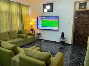 a living room with a couch and a flat screen tv at John's Cottage in Apenkwa