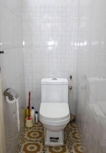 a bathroom with a toilet in a white tiled room at John's Cottage in Apenkwa