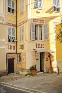 ein gelbes Gebäude mit weißen Fenstern und einer Tür in der Unterkunft B&B Giardinidivale a 2 chilometri da Finale Ligure in Borgio Verezzi