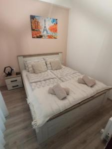 uma cama com lençóis brancos e almofadas num quarto em Apartman Zara em Jagodina