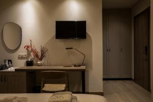 a hotel room with a desk and a television on the wall at Μikri Arktos Boutique Hotel in Dhimitsana