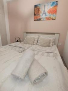 Una cama blanca con toallas en un dormitorio en Apartman Zara en Jagodina
