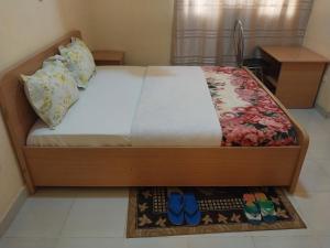 - un lit avec un cadre en bois et des chaussures bleues au sol dans l'établissement Centre d'Accueil Bonne Esperance Rwanda, à Kigali