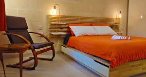 een slaapkamer met een bed en een stoel bij Unique New Apartment - Victoria - Gozo in Victoria