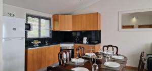 a kitchen with a table with chairs and a refrigerator at Madeira Mountain Paradise - Casa da Levada do Arco in Arco da Calheta