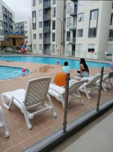 two people sitting on chairs near a swimming pool at Comodidad y tranquilidad in Ibagué