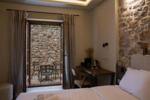 a hotel room with a bed and a balcony with a table at Μikri Arktos Boutique Hotel in Dhimitsana