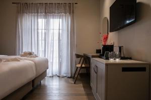a bedroom with a bed and a desk with a television at Μikri Arktos Boutique Hotel in Dhimitsana