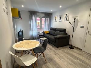 een woonkamer met een tafel en een bank bij Apartamento Playa San Lorenzo Garaje opcional in Gijón